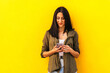 © PEDROMERINO - young stylish woman using her mobile leaning on a yellow wall