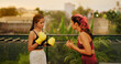 Indian Asian Hindu gen z young woman teach teen girl sport class learn hand fist punch air outdoor home healthy boxer adult female wear boxing gloves do effort beating self fight warm up workout house