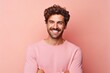 Portrait of a handsome young man smiling and looking at camera against pink background
