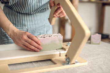 Wall Mural - Women's hands cut homemade natural soap on a professional wood cutter. A means of eco-friendly hygiene