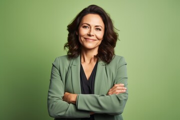 Wall Mural - Portrait of mature business woman with crossed arms against green background.