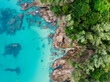 View from above, stunning aerial view of a rocky coastline surrounded by palm trees and bathed by a turquoise water. Phuket, Thailand.