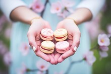hands holding raspberry macarons, blurred garden background