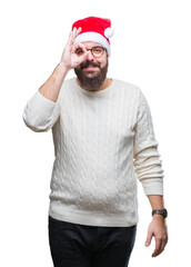 Poster - Young caucasian man wearing christmas hat and glasses over isolated background doing ok gesture with hand smiling, eye looking through fingers with happy face.