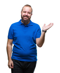 Sticker - Young caucasian hipster man wearing blue shirt over isolated background smiling cheerful presenting and pointing with palm of hand looking at the camera.