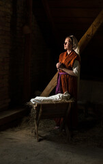 Canvas Print - Mary sits in the stable near the manger with the baby