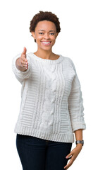 Sticker - Beautiful young african american woman wearing sweater over isolated background smiling friendly offering handshake as greeting and welcoming. Successful business.