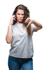 Sticker - Young brunette girl talking on smartphone over isolated background with angry face, negative sign showing dislike with thumbs down, rejection concept