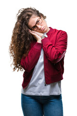 Poster - Beautiful brunette curly hair young girl wearing jacket and glasses over isolated background sleeping tired dreaming and posing with hands together while smiling with closed eyes.