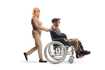 Wall Mural - Middle aged woman pushing a senior with a broken arm in a wheelchair