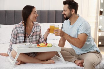 Wall Mural - Happy couple having breakfast on bed at home