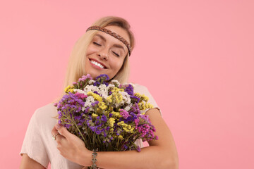 Poster - Portrait of smiling hippie woman with bouquet of flowers on pink background. Space for text