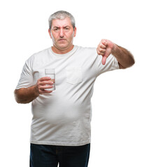 Canvas Print - Handsome senior man drinking glass of water over isolated background with angry face, negative sign showing dislike with thumbs down, rejection concept