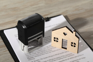 Sticker - Notary contract. Stamp, figure of house and documents on wooden table, closeup