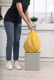 Fototapeta  - Woman taking garbage bag out of trash bin in kitchen, closeup