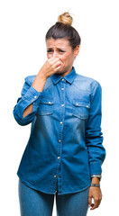 Canvas Print - Young beautiful woman over isolated background smelling something stinky and disgusting, intolerable smell, holding breath with fingers on nose. Bad smells concept.