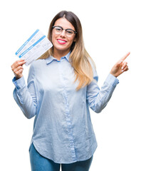 Wall Mural - Young beautiful woman holding boarding pass over isolated background very happy pointing with hand and finger to the side