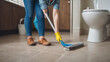 Young housekeeper cleaning floor mobbing holding mop and plastic bucket with brushes, gloves and detergents in the bath room house floor,
