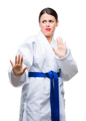 Poster - Young beautiful woman wearing karate kimono uniform over isolated background afraid and terrified with fear expression stop gesture with hands, shouting in shock. Panic concept.