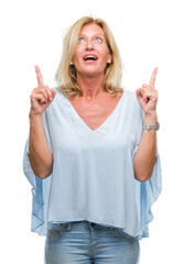 Poster - Middle age blonde business woman over isolated background amazed and surprised looking up and pointing with fingers and raised arms.