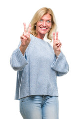 Sticker - Middle age blonde woman wearing winter sweater over isolated background smiling looking to the camera showing fingers doing victory sign. Number two.