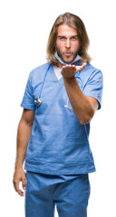 Canvas Print - Young handsome doctor man with long hair over isolated background looking at the camera blowing a kiss with hand on air being lovely and sexy. Love expression.