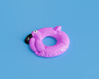 © Antonio Solano - deflated pink flamingo pool float isolated against a solid blue background, summer preparation concept.