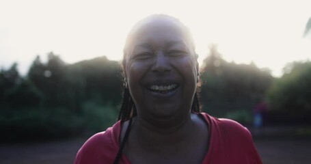 Wall Mural - Happy senior african woman smiling on camera during sunset at city park