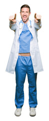 Poster - Handsome doctor man wearing medical uniform over isolated background Pointing to you and the camera with fingers, smiling positive and cheerful