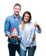 © Krakenimages.com - Young couple in love holding house over isolated background happy with big smile doing ok sign, thumb up with fingers, excellent sign