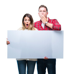 Poster - Young couple together holding blank banner over isolated background cover mouth with hand shocked with shame for mistake, expression of fear, scared in silence, secret concept