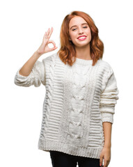 Sticker - Young beautiful woman over isolated background wearing winter sweater smiling positive doing ok sign with hand and fingers. Successful expression.