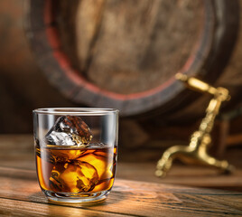 Sticker - Glass of whiskey on top of  wooden barrel and  wood barrels in cellar at the background. Sun ray falling down on it surface.