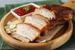 Pieces of baked pork belly served with sauce on table, closeup