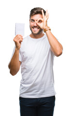 Wall Mural - Young handsome man holding notebook over isolated background with happy face smiling doing ok sign with hand on eye looking through fingers
