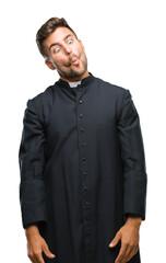 Canvas Print - Young catholic christian priest man over isolated background making fish face with lips, crazy and comical gesture. Funny expression.