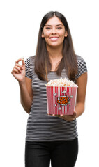 Poster - Young beautiful hispanic eating popcorn with a happy face standing and smiling with a confident smile showing teeth