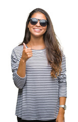 Canvas Print - Young beautiful arab woman wearing sunglasses over isolated background doing happy thumbs up gesture with hand. Approving expression looking at the camera with showing success.