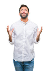 Wall Mural - Adult hispanic man over isolated background crazy and mad shouting and yelling with aggressive expression and arms raised. Frustration concept.