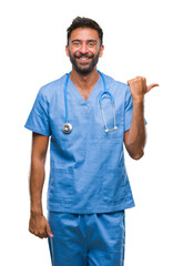 Sticker - Adult hispanic doctor or surgeon man over isolated background smiling with happy face looking and pointing to the side with thumb up.