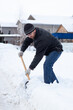 © Оксана Рязанова - A man with a snow shovel cleaning snow from a sidewalk on the street on cold winter day, doing snow removal