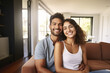 © FutureStock - Smiling couple sitting at sofa embraced at their apartment.