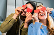 © Carla - Couple celebrating valentine's day date having fun and laughing covering their faces with red papers heart shape joying and having good connection together.