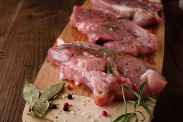 Wall Mural - a piece of fresh raw pork meat with spices on a brown wooden table. Meat with spices