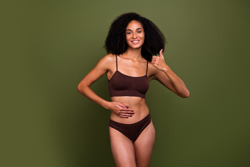 Wall Mural - No retouch photo of attractive charming healthy woman wear brown lingerie touch stomach thumb up isolated on khaki color background