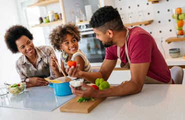 Wall Mural - Happy african american family preparing healthy food in kitchen, having fun together on weekend