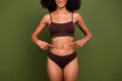Cropped no retouch photo of charming slender girl showing her thin waist isolated on khaki color background