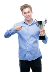 Sticker - young handsome blond man holding a trophy very happy pointing with hand and finger