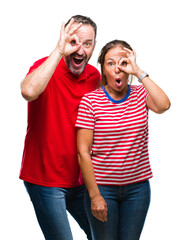 Poster - Middle age hispanic couple in love over isolated background doing ok gesture shocked with surprised face, eye looking through fingers. Unbelieving expression.