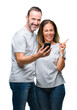 © Krakenimages.com - Middle age hispanic couple texting message on smartphone ver isolated background very happy pointing with hand and finger to the side
